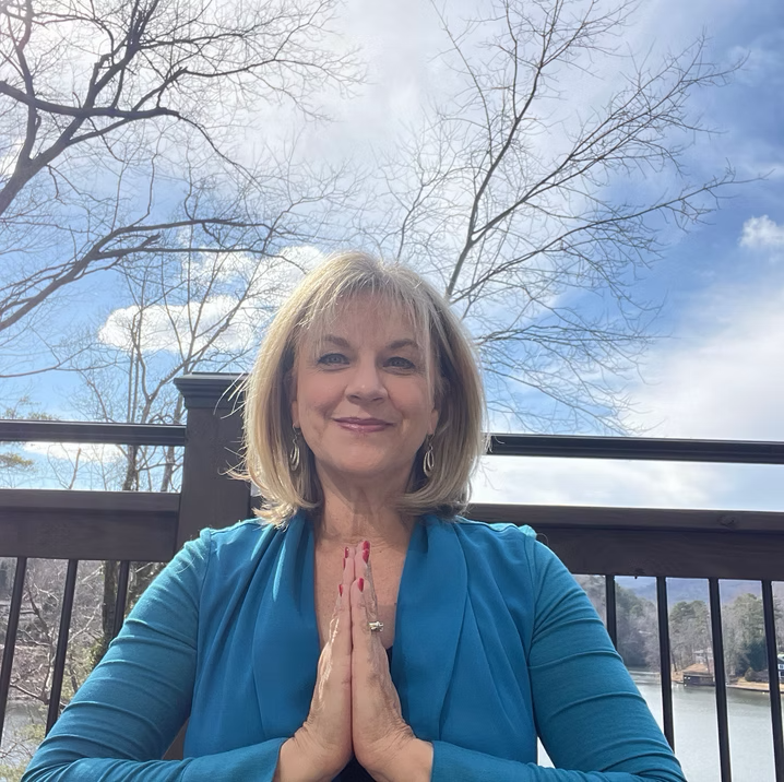 Beth Spring seated outdoors with her hands together in prayer